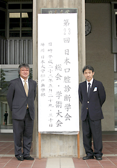 日本口腔診断学会の看板前での岩本院長と多田先生